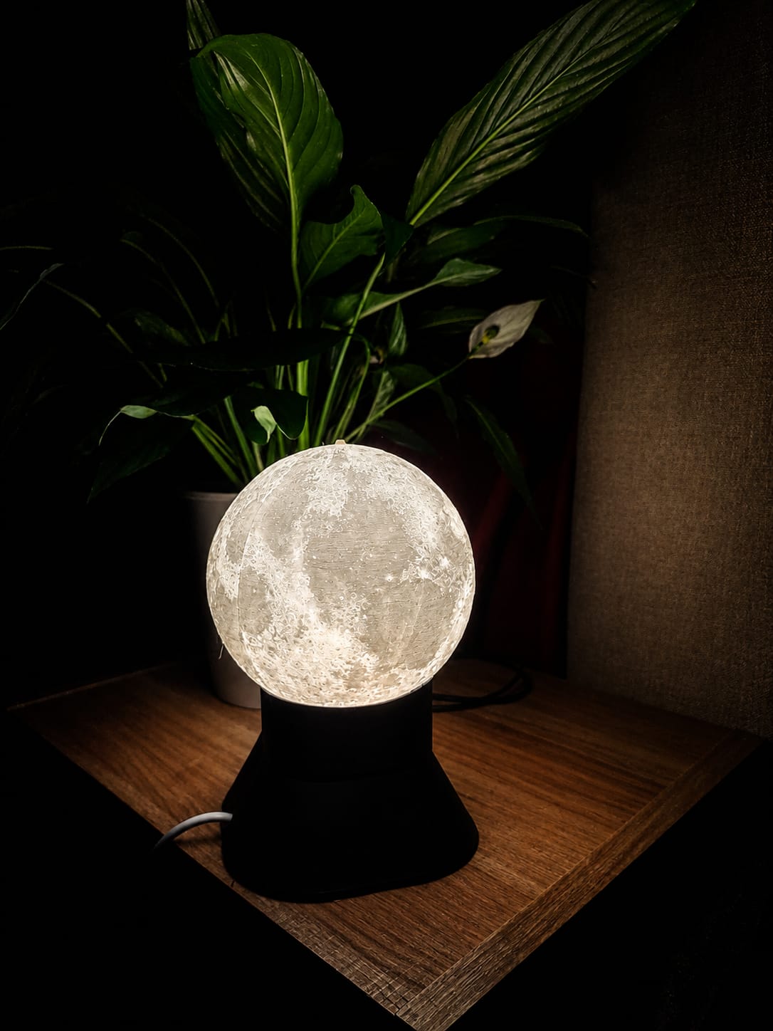 Illuminated 3D-printed moon lamp displayed in a dark room.